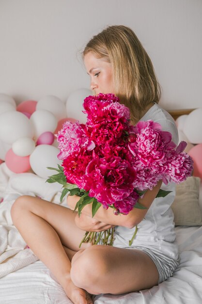 pretty young woman  at home  in bedroom in bed holding flowers take a selfie by mobile phone