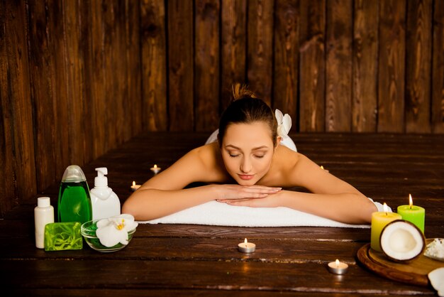 Pretty young woman laying in spa salon with closed eyes and relaxed