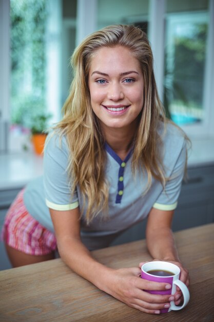 Pretty young woman leaning on table while having coffee 