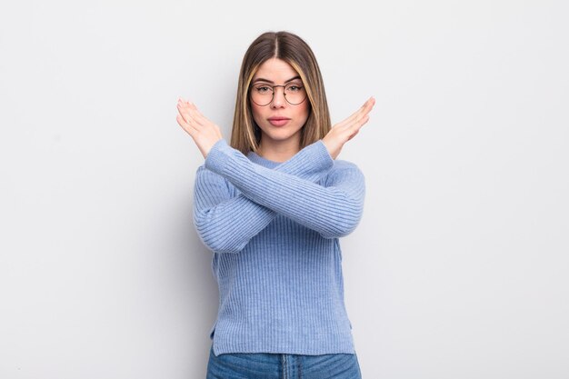 Pretty young woman looking annoyed and sick of your attitude saying enough hands crossed up front telling you to stop