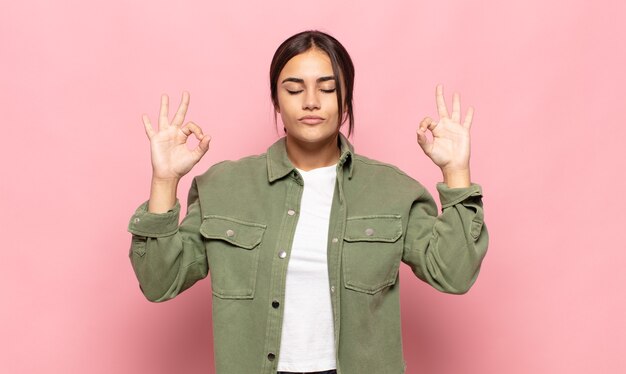 Pretty young woman looking concentrated and meditating, feeling satisfied and relaxed, thinking or making a choice