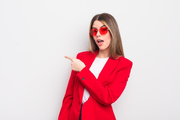 Pretty young woman looking excited and surprised pointing to the side