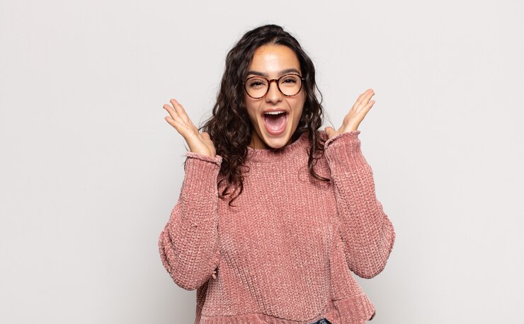 Photo pretty young woman looking happy and excited, shocked with an unexpected surprise with both hands open next to face