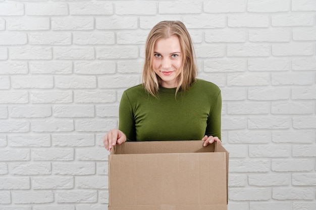 Pretty young woman looking in open cardboard box Delivering a parcel