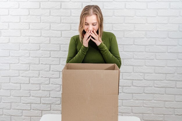 Pretty young woman looking in open cardboard box Delivering a parcel