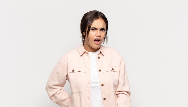 Pretty young woman looking shocked, angry, annoyed or disappointed, open mouthed and furious