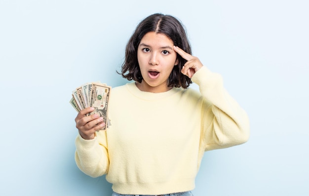 Pretty young woman looking surprised, realizing a new thought, idea or concept. dollar banknotes concept