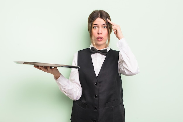 Pretty young woman looking surprised, realizing a new thought, idea or concept. waiter with a tray concept