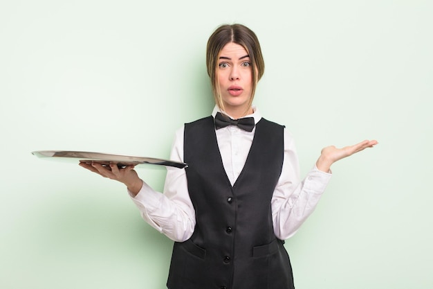 pretty young woman looking surprised and shocked, with jaw dropped holding an object. waiter with a tray concept