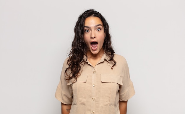 Pretty young woman looking very shocked or surprised, staring with open mouth saying wow