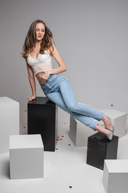 Pretty young woman lying on black boxes, isolated on grey wall