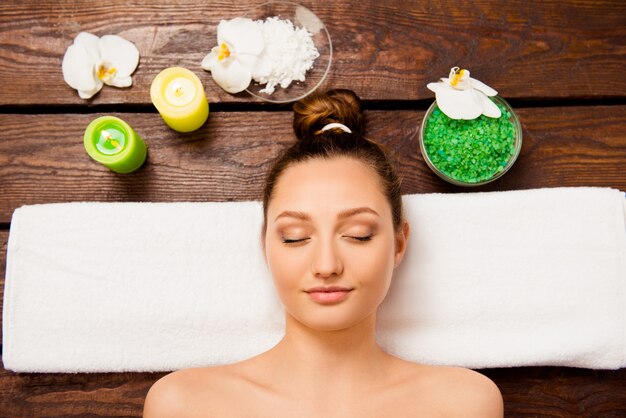 Pretty young woman lying in sauna and relaxing