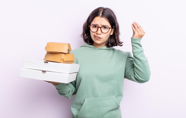 Pretty young woman making capice or money gesture, telling you to pay. fast food take away concept