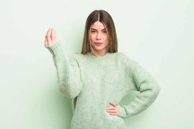 Pretty young woman making capice or money gesture, telling you to pay