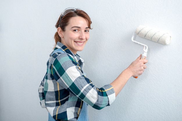 Pretty young woman painting the wall