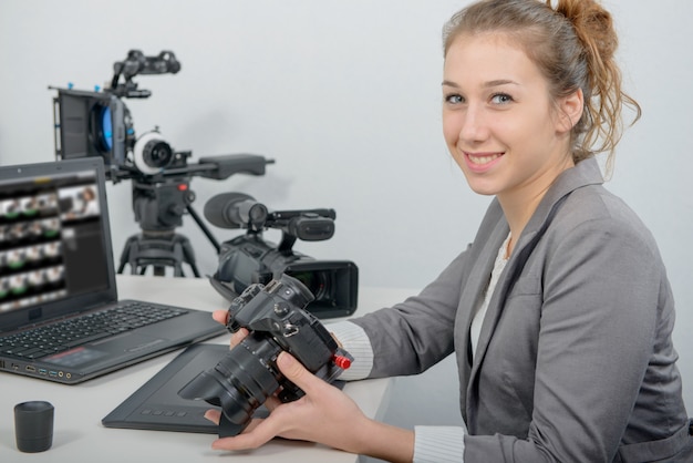 Pretty young woman photographer with camera in office