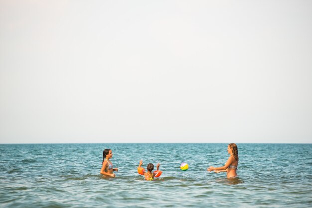 Photo pretty young woman plays ball with her daughters