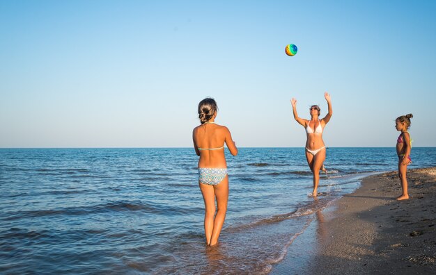 Pretty young woman plays ball with her daughters