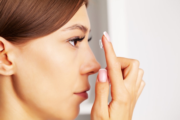 Pretty young woman puts on contact lenses for eyesight