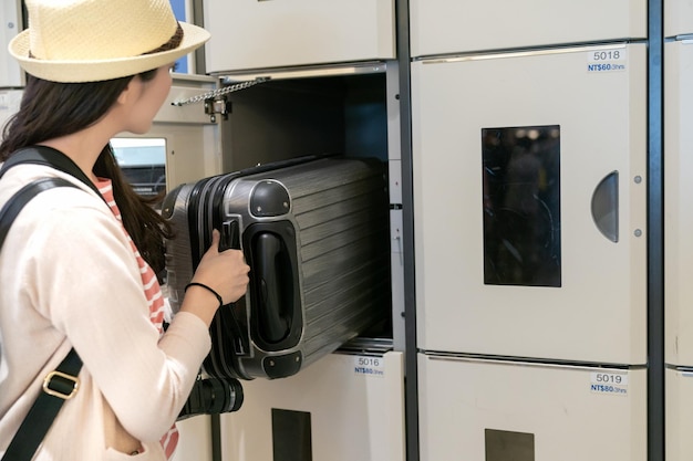 pretty young woman putting the luggage in the locker. half-body upper and back view