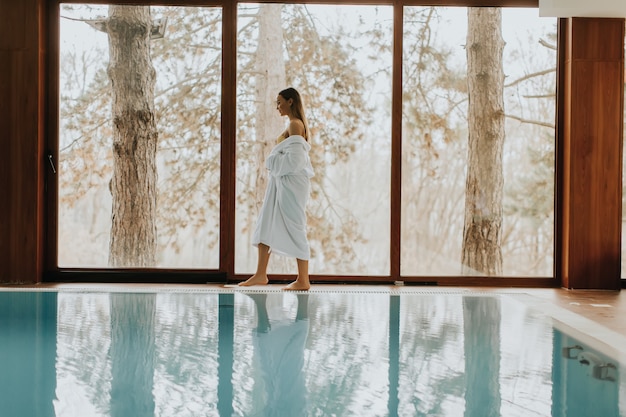 Pretty young woman relaxing by swimming pool in spa center