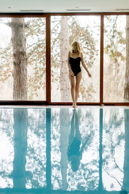 Pretty young woman relaxing by swimming pool in spa center