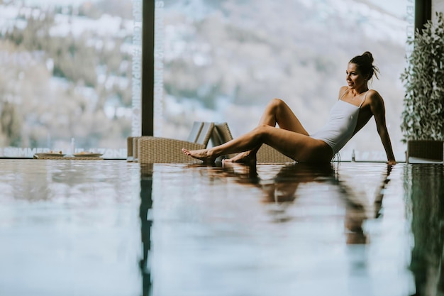 Красивая молодая женщина отдыхает у бассейна в пейзажном бассейне в зимнее время