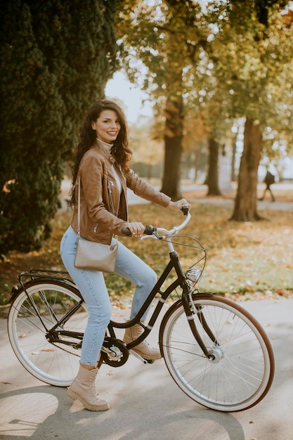 Pretty young woman riding bicycle on autumn day