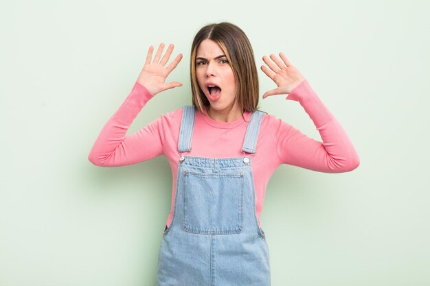 Photo pretty young woman screaming in panic or anger, shocked, terrified or furious, with hands next to head