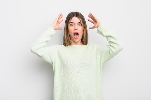 Pretty young woman screaming with hands up in the air, feeling furious, frustrated, stressed and upset