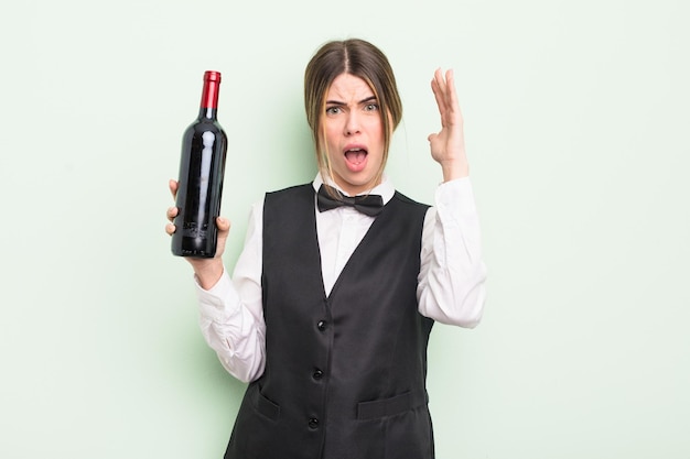 pretty young woman screaming with hands up in the air. waiter and wine bottle concept