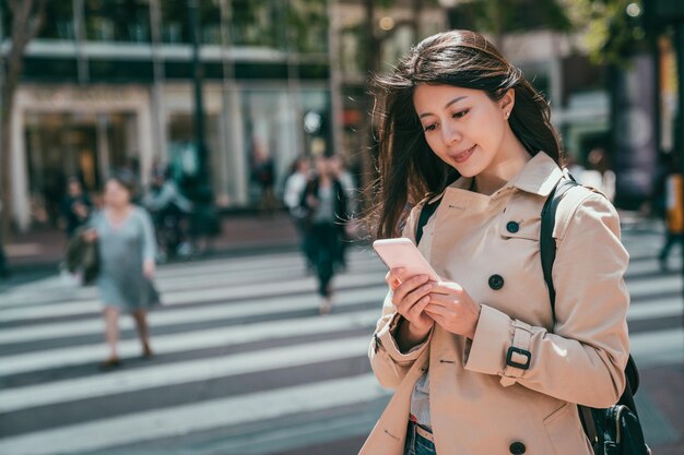 かなり若い女性が友達にメッセージを送り、仕事の後に通りに立っています。