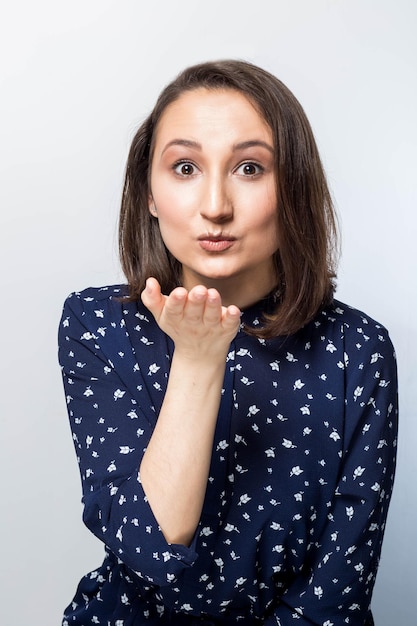 Pretty young woman sends an air kiss white background. Positive emotions, feelings