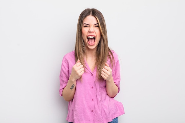 pretty young woman shouting aggressively with annoyed, frustrated, angry look and tight fists, feeling furious