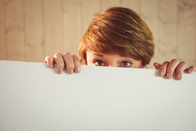 Photo pretty young woman showing sign hiding her face behind sign