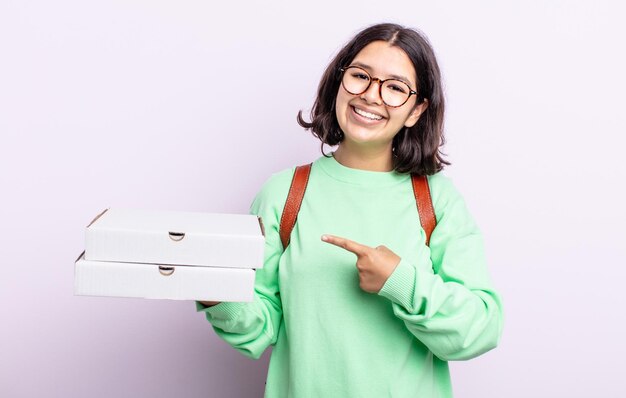 Pretty young woman smiling cheerfully, feeling happy and pointing to the side. take away concept