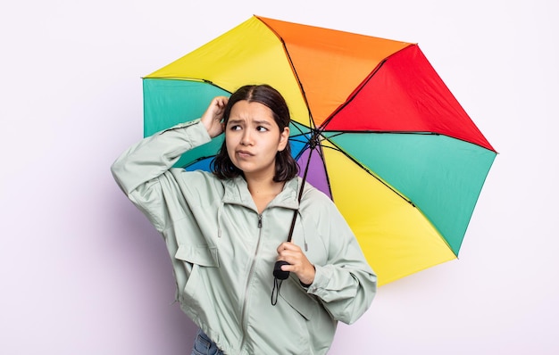 幸せに笑って、空想にふけるか、疑うかなり若い女性。雨と傘のコンセプト