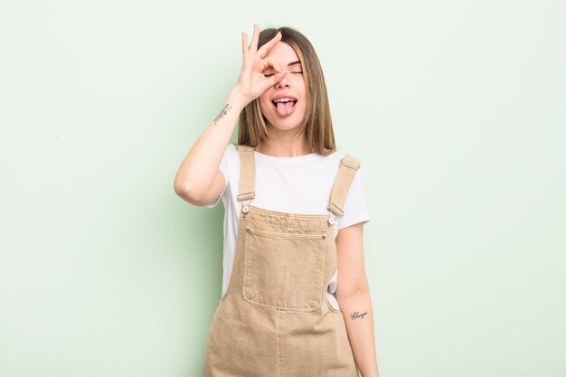 Pretty young woman smiling happily with funny face, joking and looking through peephole, spying on secrets