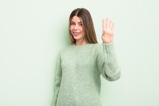 Pretty young woman smiling and looking friendly showing number four