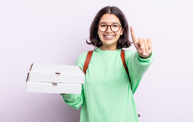 Pretty young woman smiling and looking friendly, showing number one. take away concept