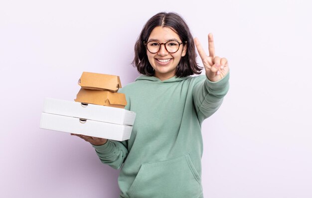 꽤 젊은 여자 웃 고 친절 찾고 번호 2를 보여줍니다. 패스트 푸드 테이크 아웃 개념