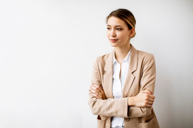 現代のオフィスの白い壁のそばに立っているかなり若い女性