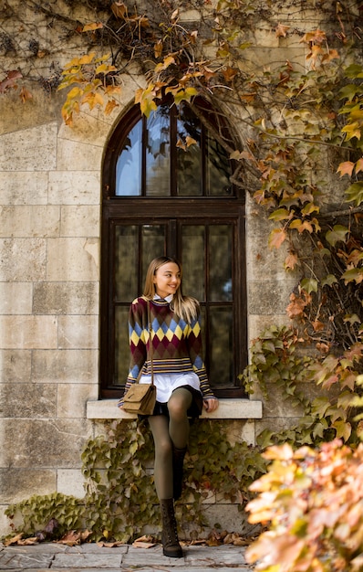 Pretty young woman standing outside at sunny autumn day