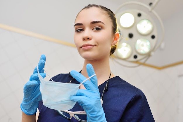 Foto bella giovane donna in una tuta chirurgica in guanti di gomma blu sullo sfondo di una lama chirurgica