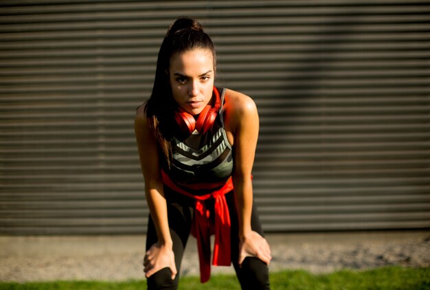 Pretty young woman takes a break after running in urban area