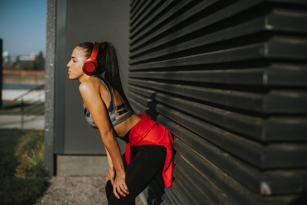 Photo pretty young woman takes a break after running in urban area