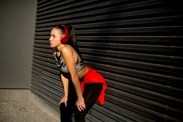 Pretty young woman takes a break after running in urban area