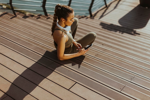 Pretty young woman takes a break after running in urban area