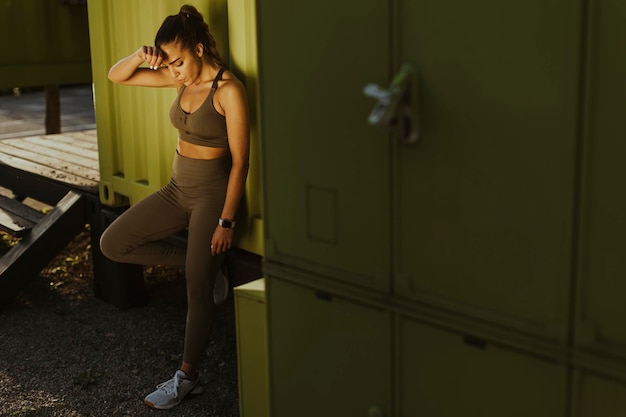 Pretty young woman takes a break after running in urban area