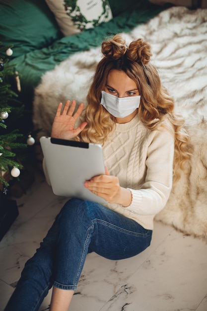 Una bella giovane donna parla con i suoi amici e la sua famiglia con un tablet durante la quarantena